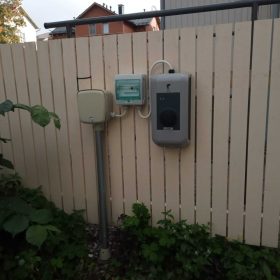 Sähköauton latausasema piha-aidassa.