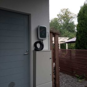 Sähköauton latausasema omakotitalon seinässä.