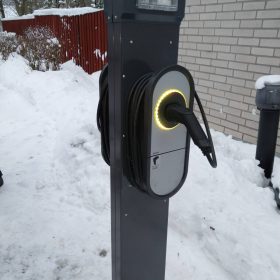 Sähköauton lataustolppa kiinteistön pihassa.