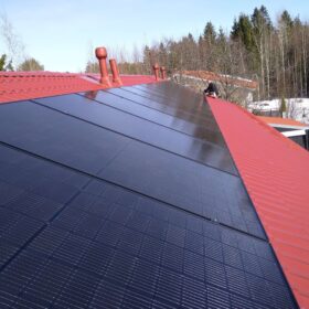 Aurinkosähköpaneelien asennus rivitalon katolle.